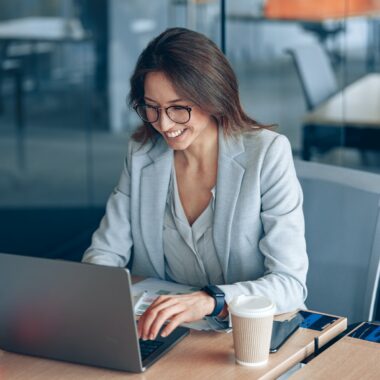 Smiling business lady working on laptop in the corporate company at modern office