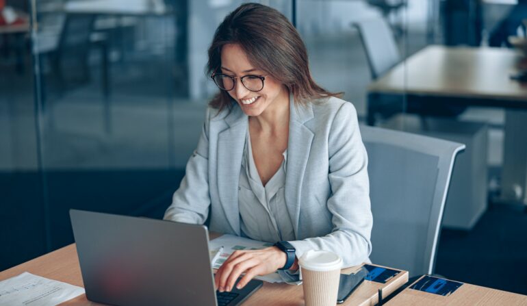Smiling business lady working on laptop in the corporate company at modern office